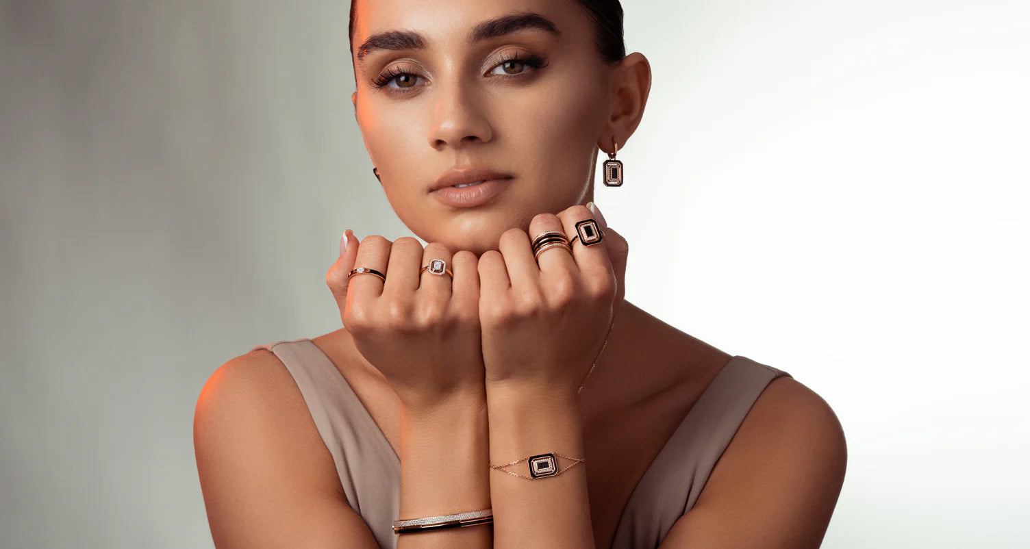 Model wears Canadian-made 14K rose gold, diamond, and black enamel jewelry including rings, dangle earrings, and a bracelet.