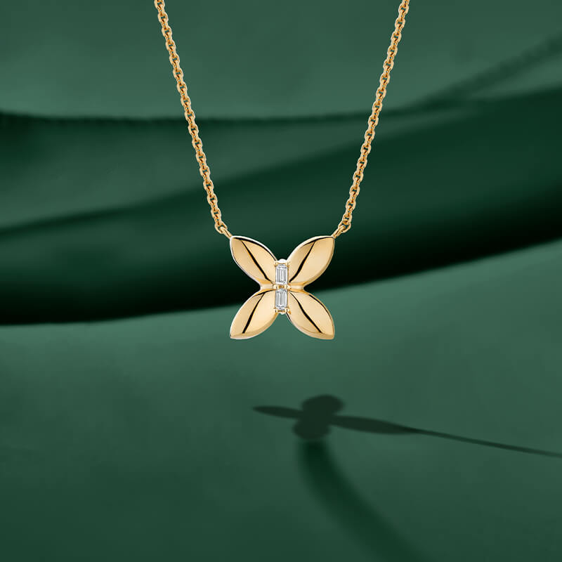 ecksand yellow gold butterfly chain necklace with diamond accents on green background