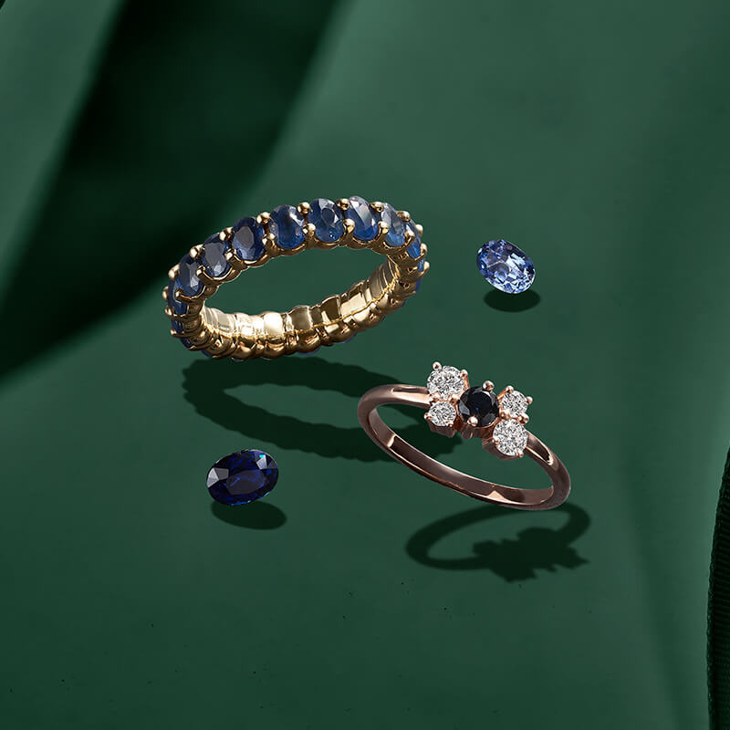 ecksand rose and yellow gold rings with diamonds and blue sapphires on green background, gemstone rings