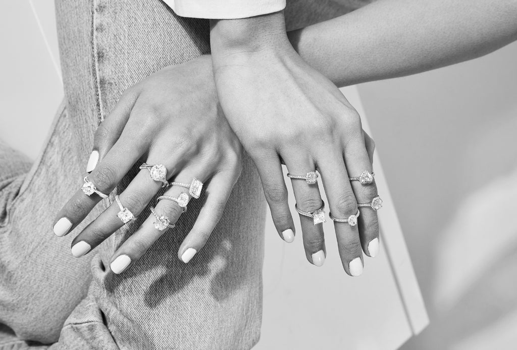 A black and white photo of a model wearing a number of Ecksand engagement rings.