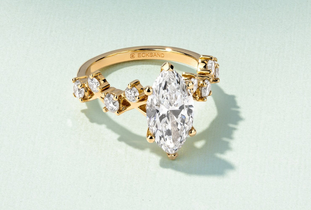 a yellow gold interlocking engagement ring with marquise centre diamond and canadian national mark engraving on green background