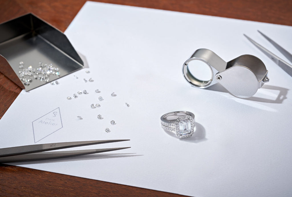 A Canadian-made emerald-cut diamond engagement ring in 18K white gold on a jeweler's workbench in our Montreal atelier.