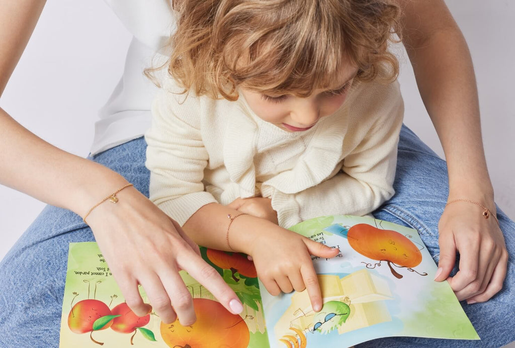 A mother and child read together, wearing matching Canadian-made bracelets in Rose Gold and Yellow Gold.