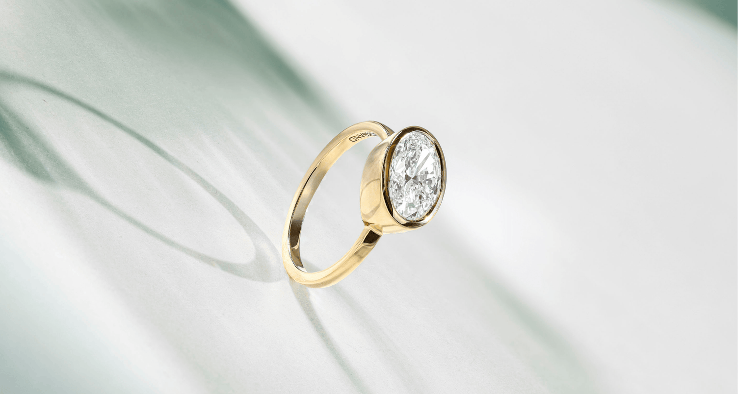a canadian-made 18k yellow gold east west bezel set oval diamond engagement ring from ecksand's classic solitaire collection