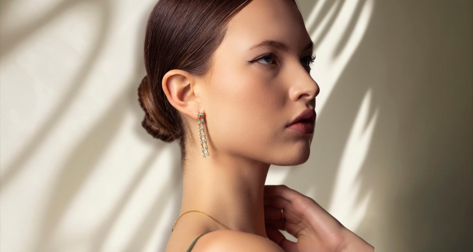 ecksand gold dangle earring with diamonds on model on yellow background