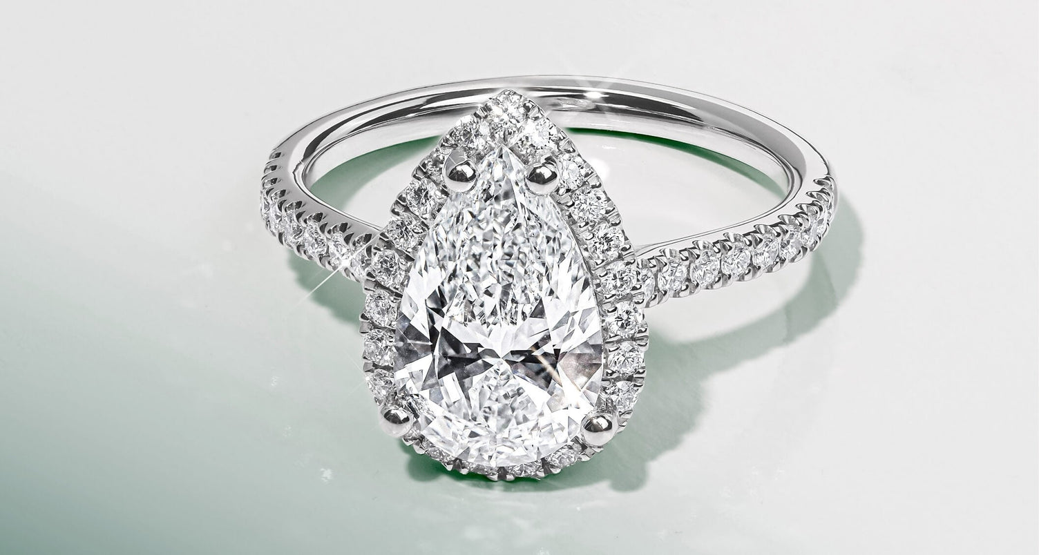 a canadian-made 18k white gold diamond halo engagement ring with diamond pavé band and pear cut diamond centre stone