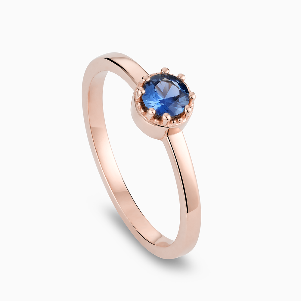 Angled view of Ecksand's Round Blue Sapphire Stackable Ring with Milgrain Halo in 18k Rose Gold