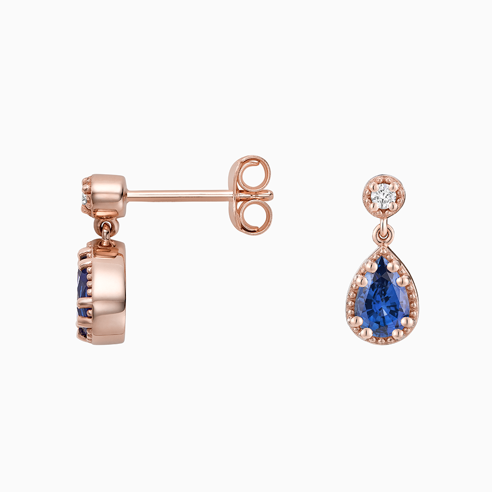 Angled view of Ecksand's Pear Blue Sapphire Stud Earrings with Milgrain Halo and Diamond Accent in 18k Rose Gold, Lab-grown VS2+/ F+