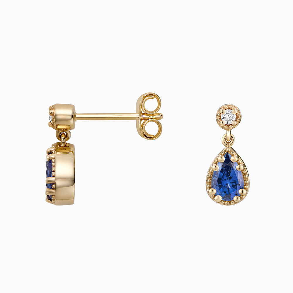 Angled view of Ecksand's Pear Blue Sapphire Stud Earrings with Milgrain Halo and Diamond Accent in 18k Yellow Gold, Lab-grown VS2+/ F+