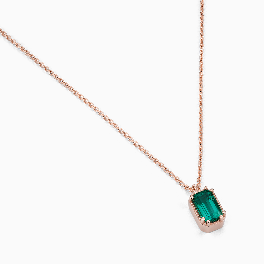 Angled view of Ecksand's Emerald Stackable Necklace with Milgrain Halo in 18k Rose Gold