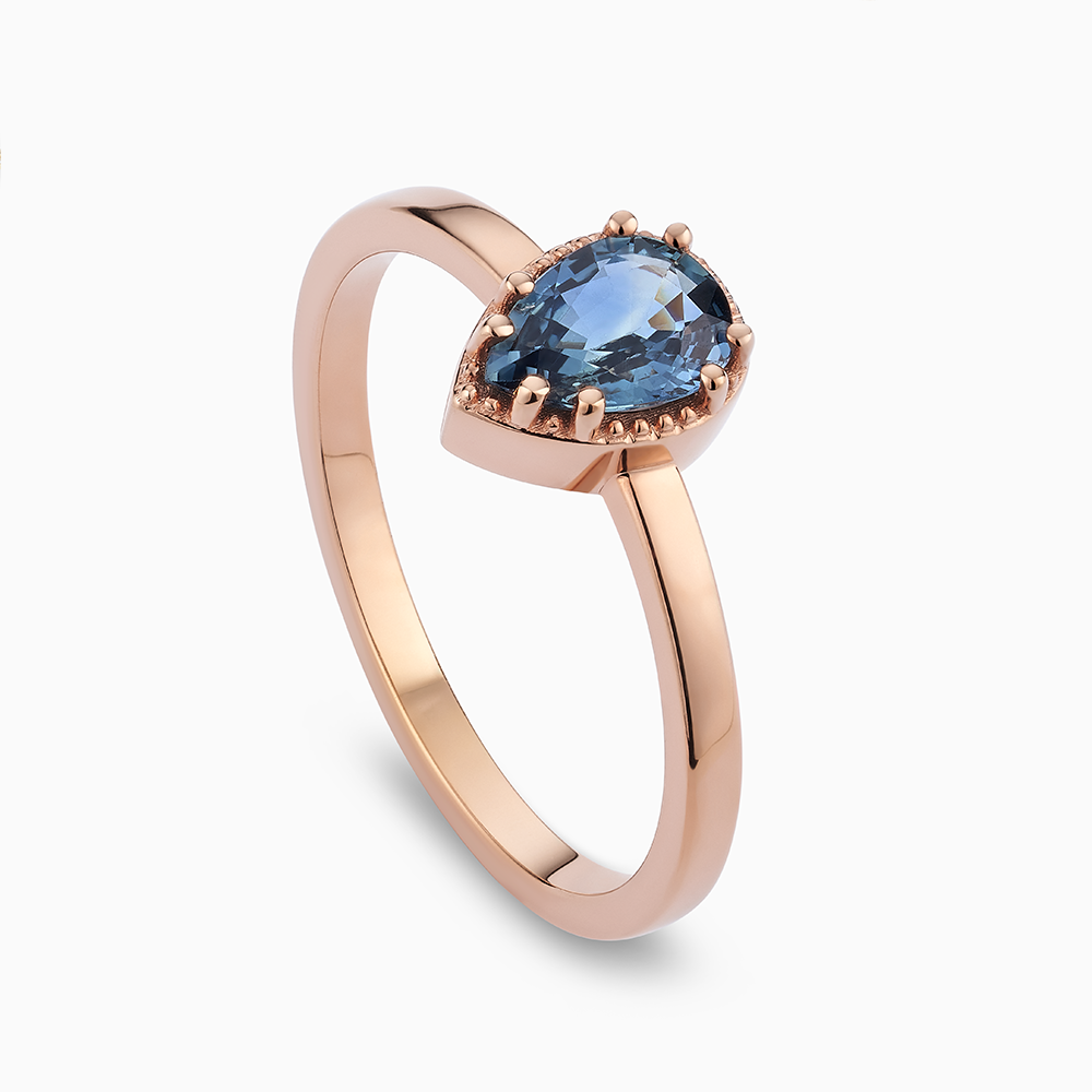 Angled view of Ecksand's Pear Montana Sapphire Stackable Ring with Milgrain Halo in 18k Rose Gold