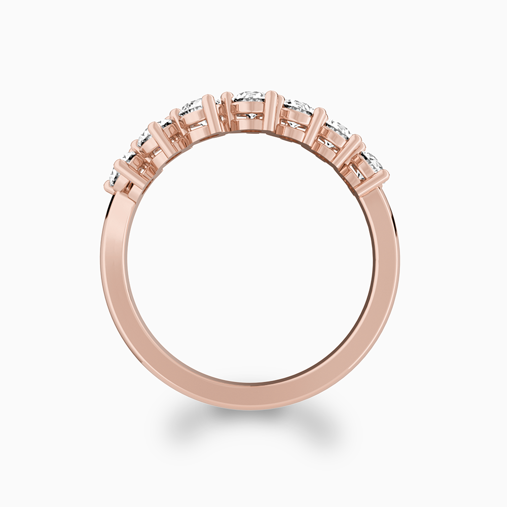 Side profile of a Canadian-made diamond wedding ring in 14K rose gold with shared prong diamonds.