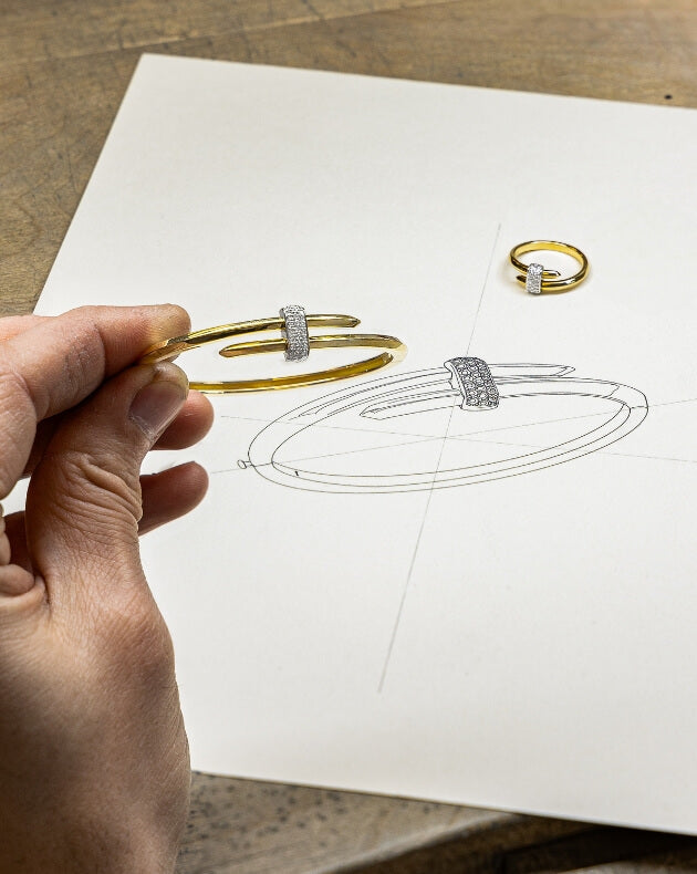jeweller reviewing the design for an ecksand yellow gold diamond bangle bracelet and yellow gold diamond duel wrap ring