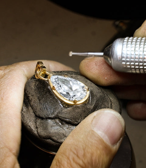 A jeweller handcrafts a Canadian-made pear diamond pendant in 18k yellow gold in the Ecksand Montreal atelier.