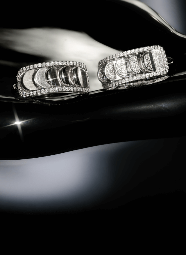 two canadian-made 18k white gold reversible diamond pave rings from ecksand's aura chrome collection on a black background