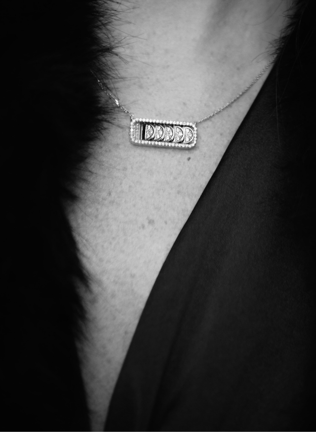 model wearing a canadian-made ecksand 18k white gold reversible diamond pave crescent necklace with a black dress and fur coat