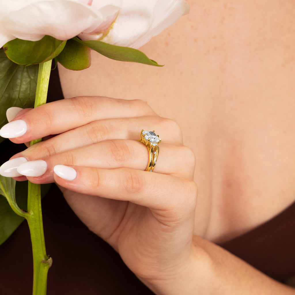 Canadian-made oval diamond engagement ring in 18K yellow gold with a split shank band, worn on a model's hand.