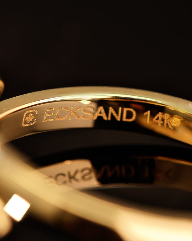 Close-up of a gold ring engraved with “ECKSAND 14K,” highlighting fine craftsmanship and polished detail.