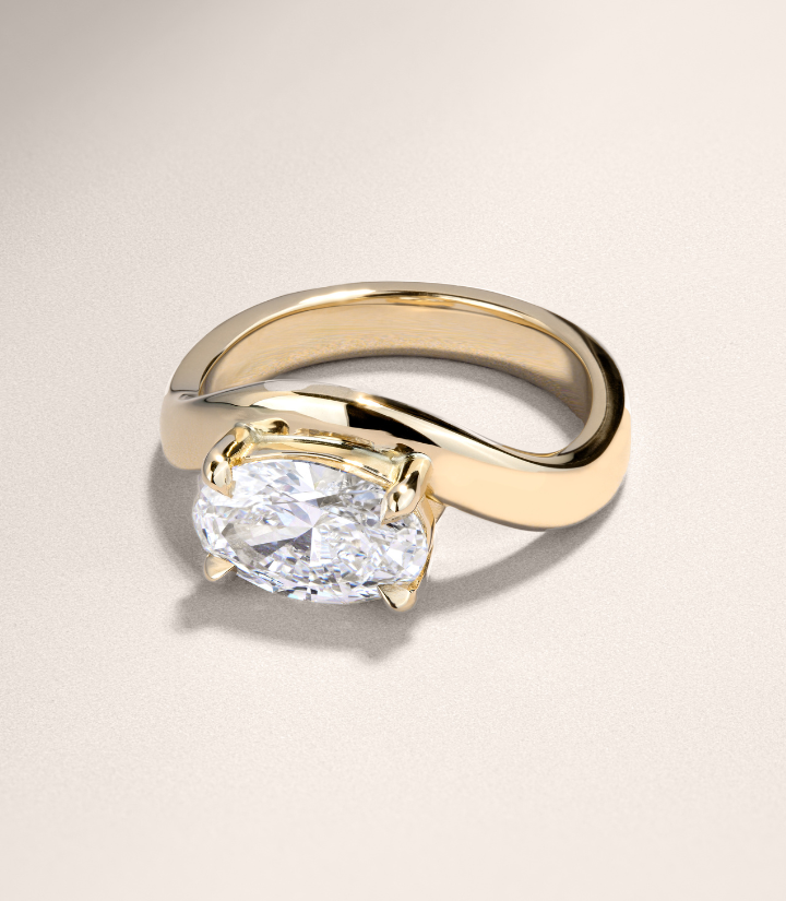 Canadian-made engagement ring with an oval diamond solitaire set on a swirling 18K yellow gold band.