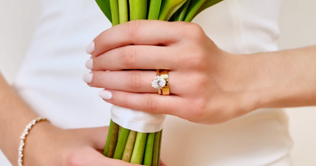 A woman wears a Canadian-made diamond engagement ring, wedding ring, and a diamond bracelet in yellow gold.