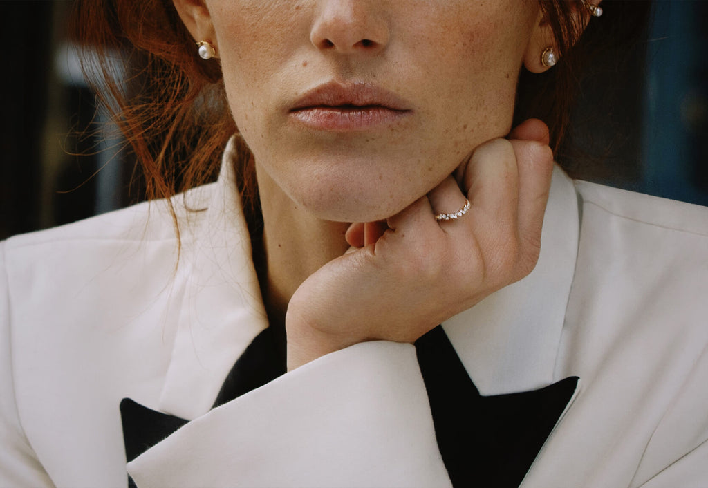 Model wearing canadian-made ecksand 18k rose gold interlocking diamond pave curved wedding ring in a white blazer