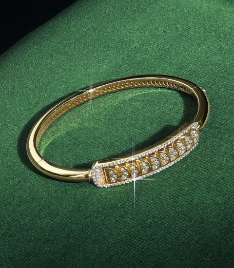 A Canadian-made 18k yellow gold diamond bangle bracelet with reversible crescent design on a green background