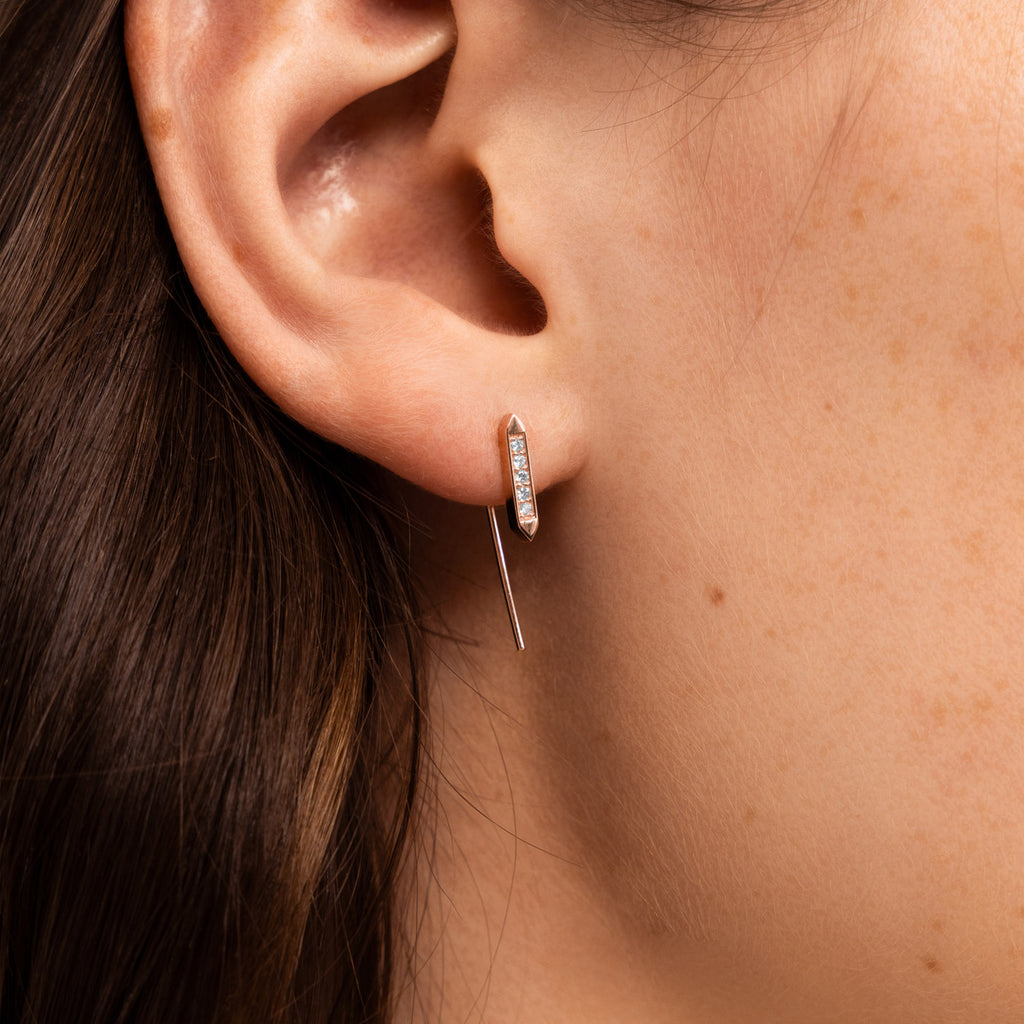 A Canadian-made Ecksand diamond bar ear climber in 14K rose gold, shown on a model's ear.