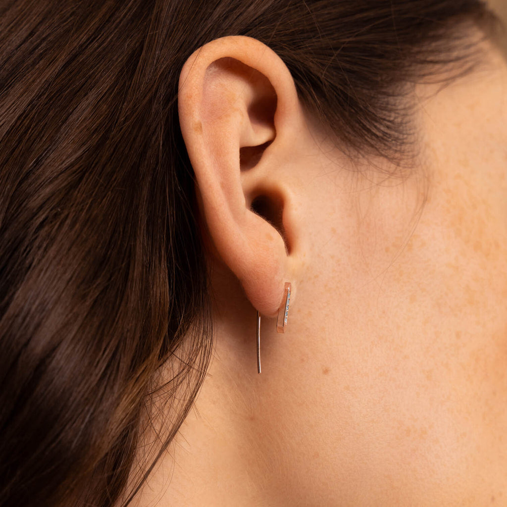 Model wearing minimalist Canadian-made 14K rose gold and diamond bar dangle earrings.