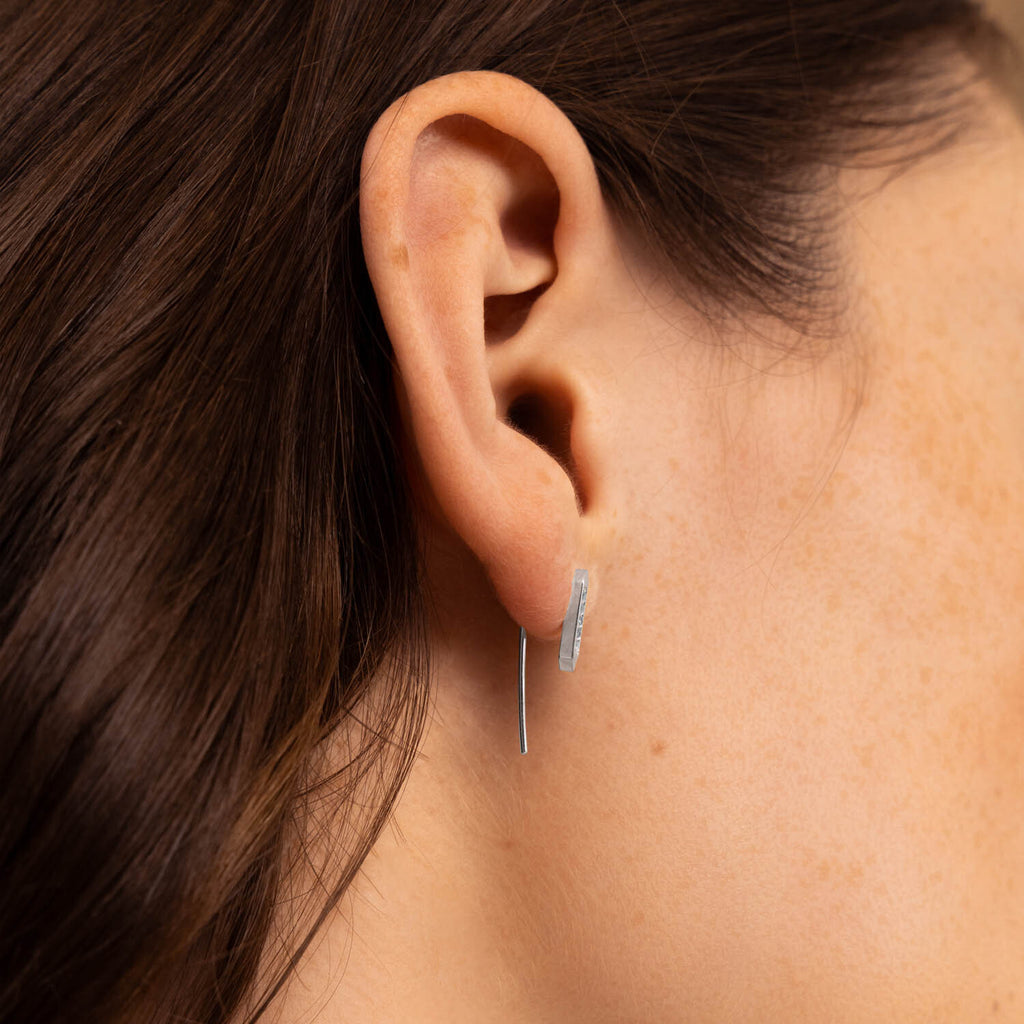 Canadian-made 18K white gold and diamond bar ear climber earring shown on a model's ear.