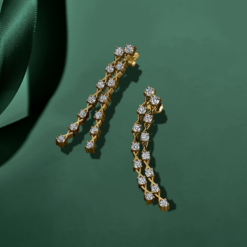 ecksand yellow gold dangle earrings with diamonds on green background