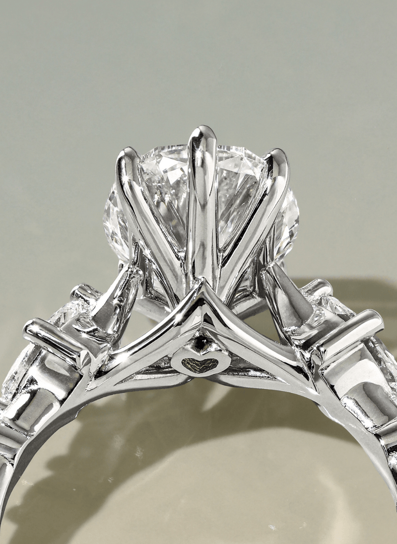 A close-up shot of a canadian-made 18k white gold solitaire engagement ring with a oval brilliant-cut diamond, set in a prong-style band on a neutral light gray background from ecksand's secret heart collection with a hidden heart