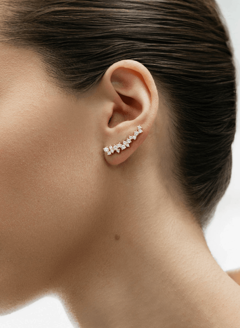 A close-up side profile of a woman's ear wearing a canadian-made 18k yellow gold asymmetrical diamond crawler earring.