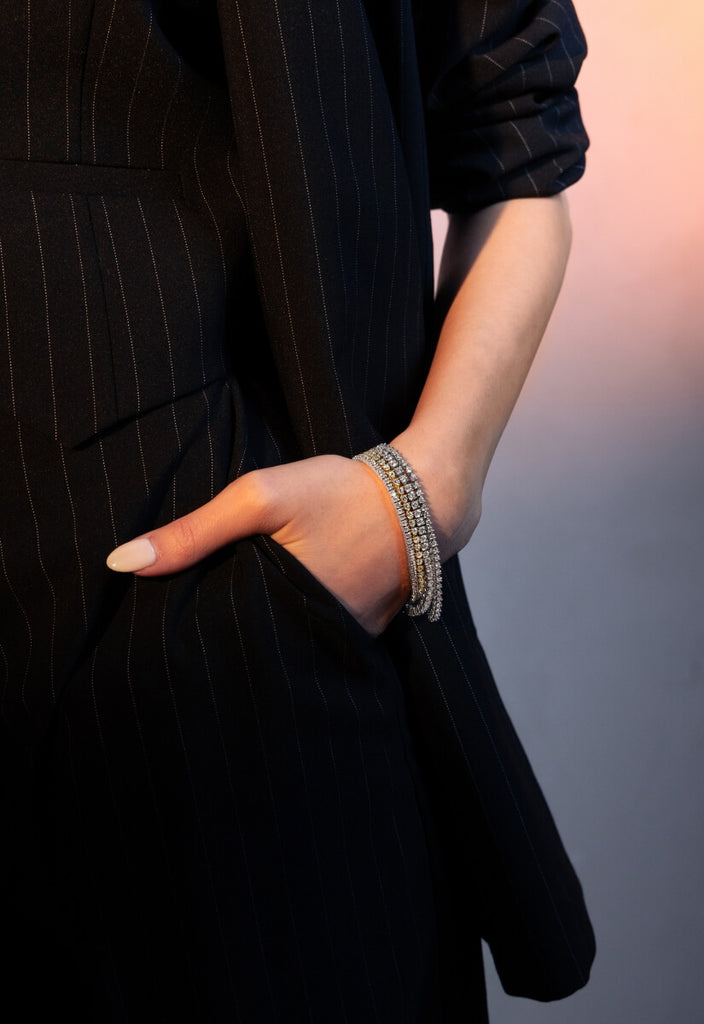 model wearing white and yellow gold diamond tennis bracelets from the ecksand starlight collection on a pink background