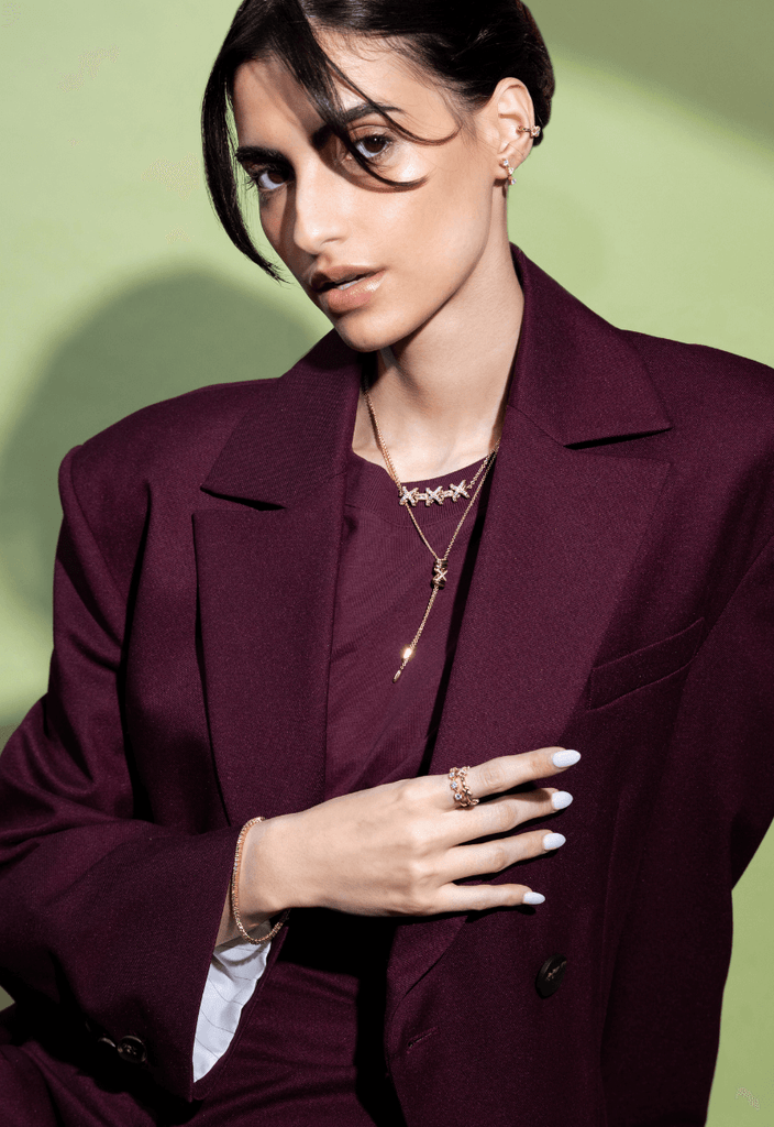 model wearing yellow gold diamond jewelry from the ecksand xo collection on a green background