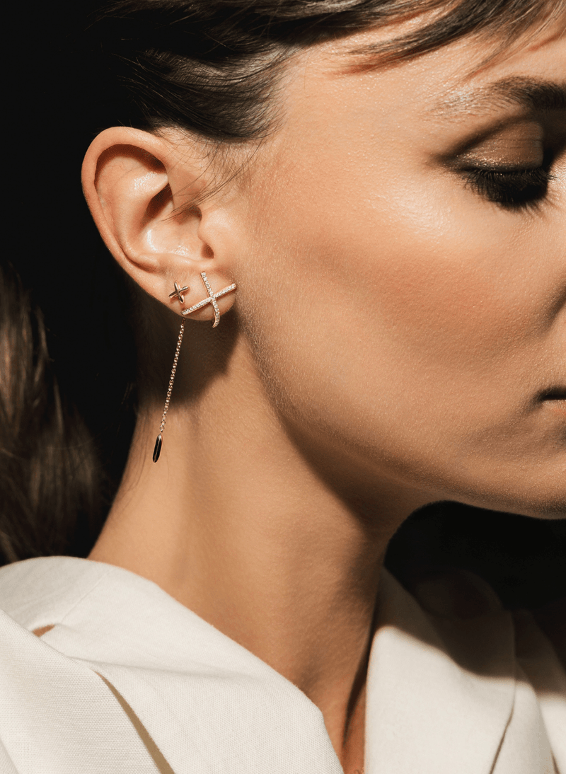 A close-up of a woman's ear and side profile wearing canadian-made 14k rose gold earrings from the mark collection.