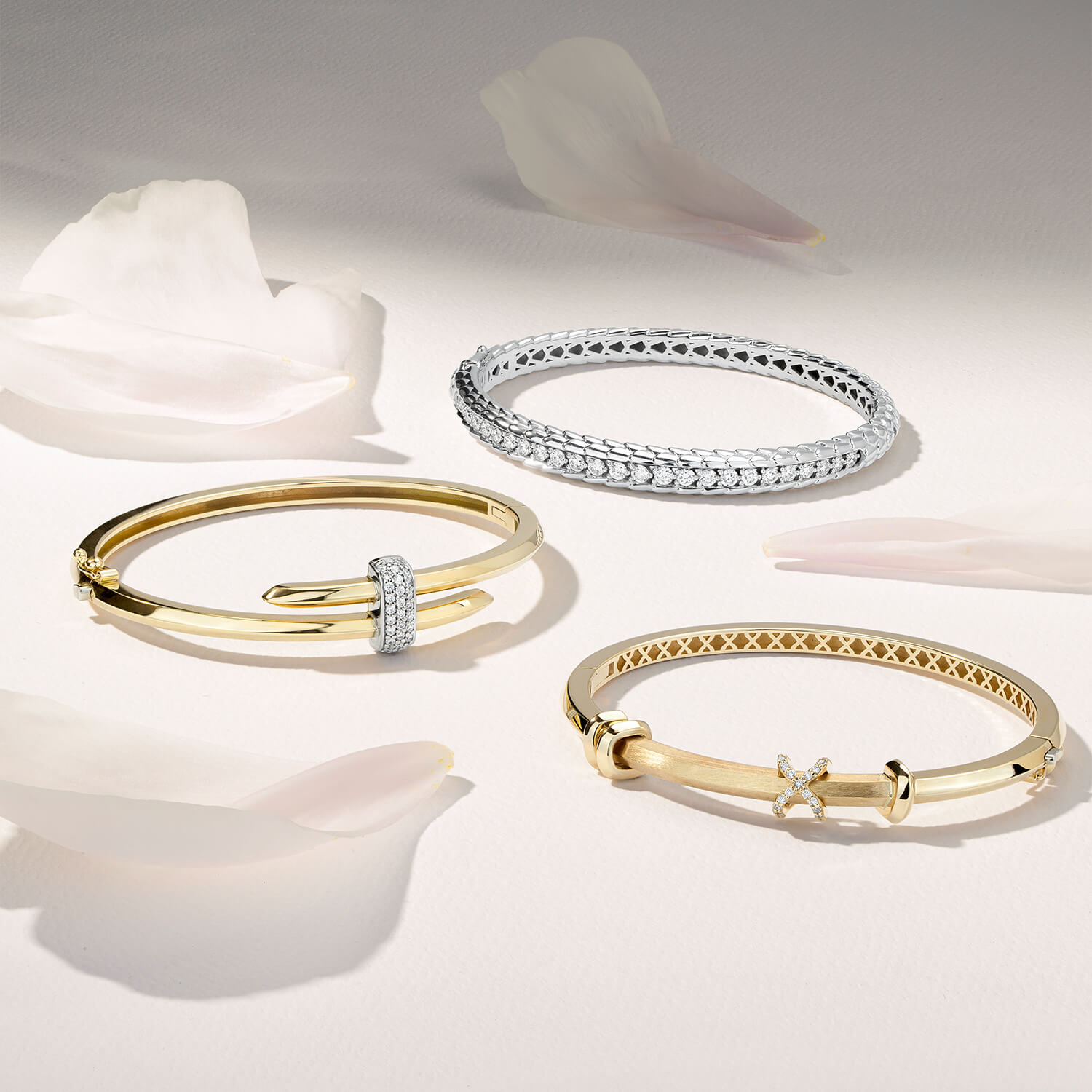Three Ecksand diamond bangles in 18K yellow gold and 18K white gold. Canadian-made fine jewelry on a white surface.
