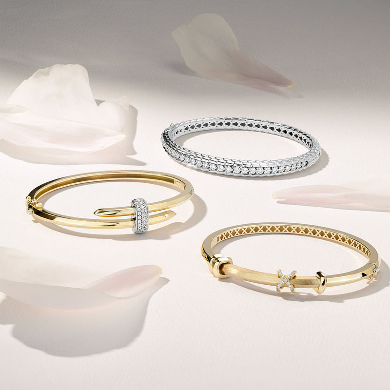 Three Ecksand diamond bangles in 18K yellow gold and 18K white gold. Canadian-made fine jewelry on a white surface.