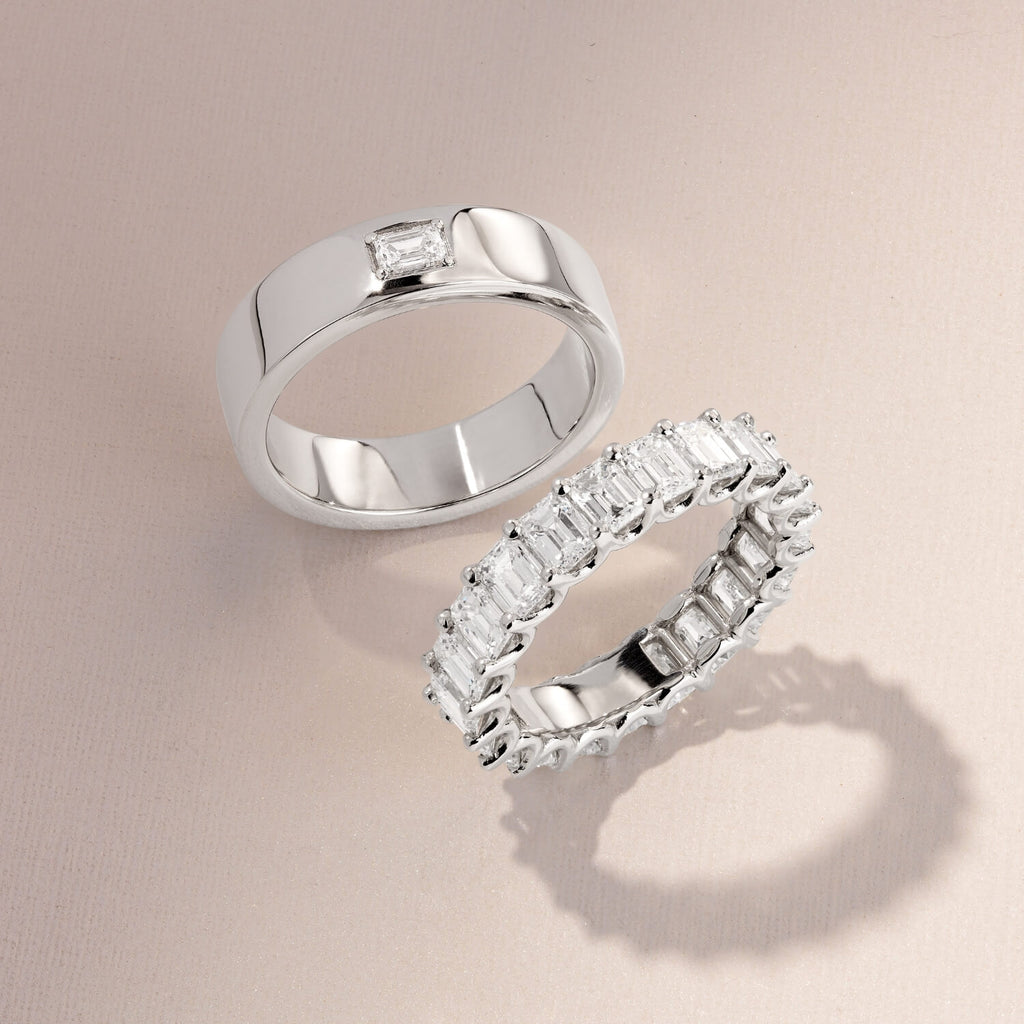 an ecksand white gold men's wedding band with a baguette diamond and a white gold diamond eternity ring on a brown background