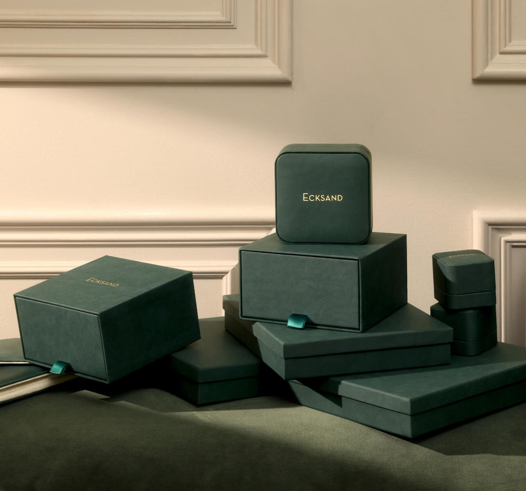 ecksand green jewelry gift boxes on a green couch in a beige room