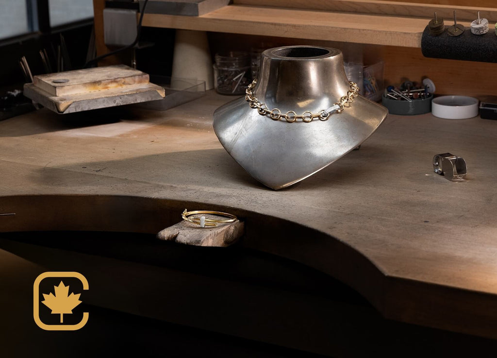 yellow gold duel diamond bangle next to yellow gold diamond chain necklace on a wooden workbench in the ecksand atelier