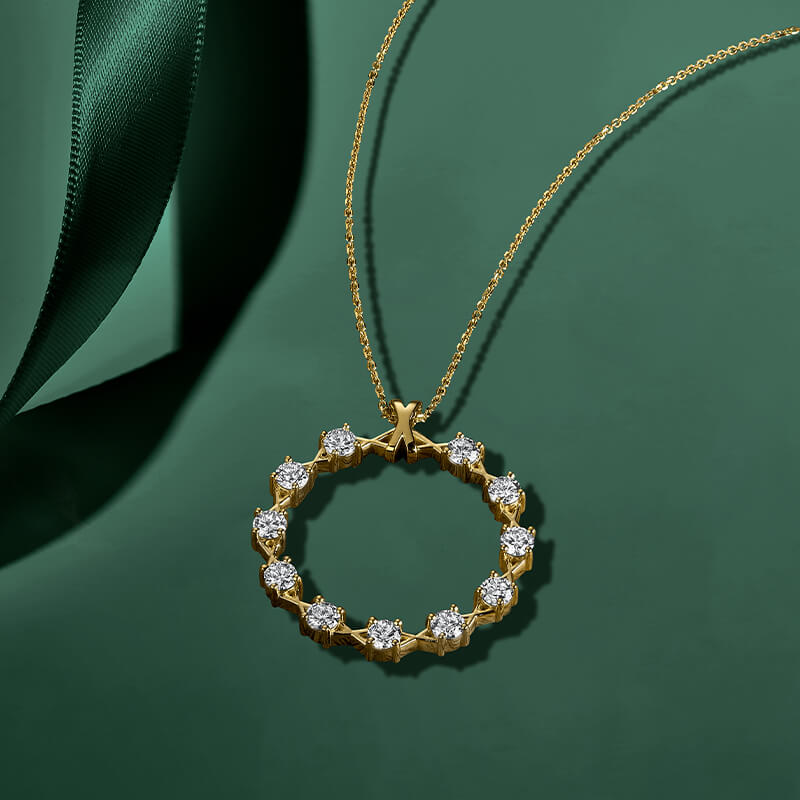 ecksand yellow gold circle chain necklace with round diamond accents on green background