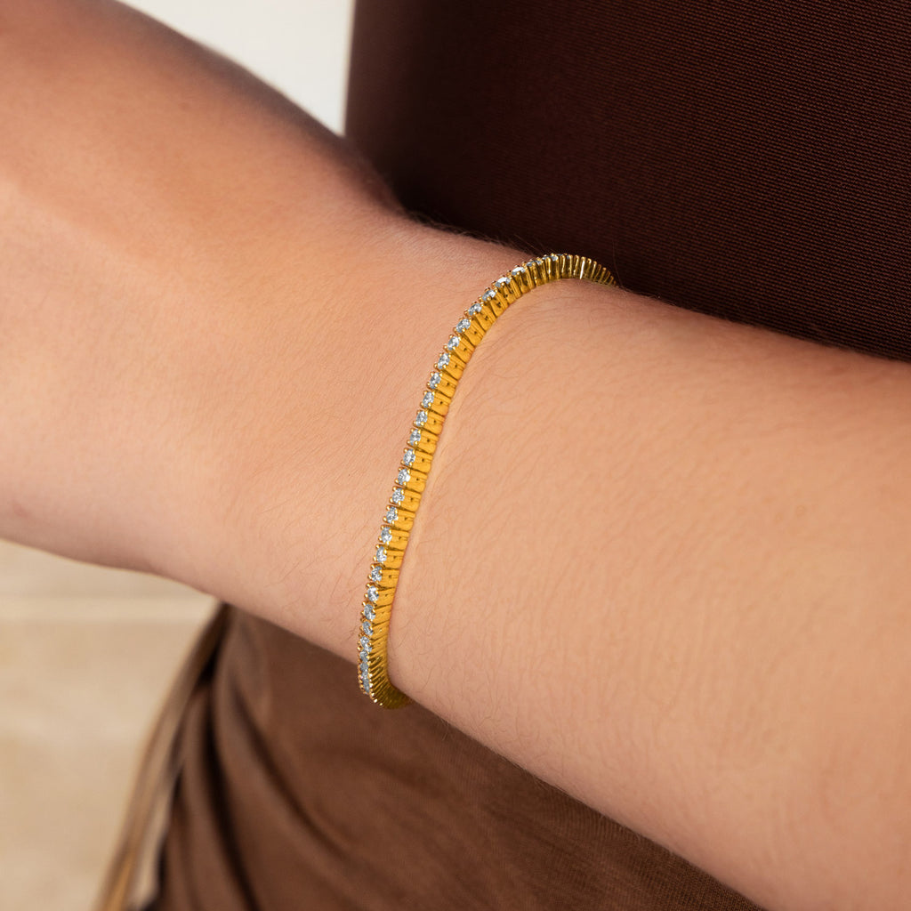 Canadian-made diamond tennis bracelet in 18K yellow gold worn on a model's wrist.