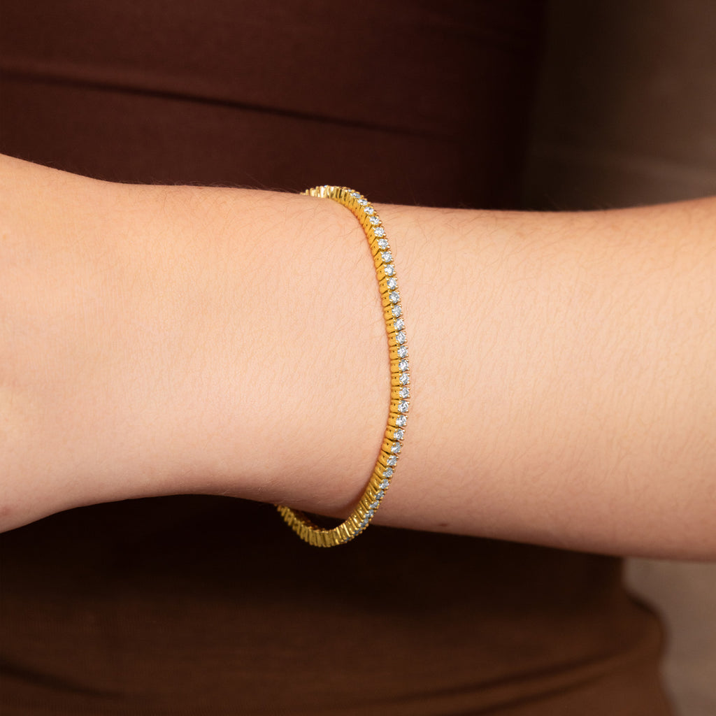 A Canadian-made Ecksand diamond tennis bracelet in 18K yellow gold shown on a model's wrist.