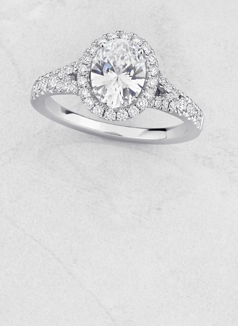 a canadian-made 18k white gold diamond halo engagement ring with split shank diamond pave band and oval cut diamond centre stone
