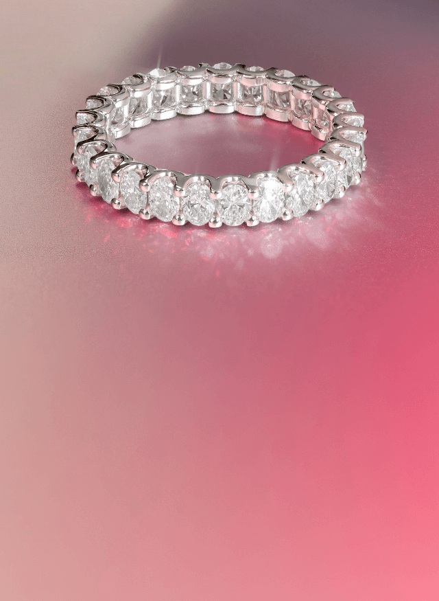 a canadian-made 18k white gold oval diamond eternity ring on a pink background