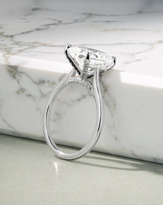 Canadian-made emerald-cut diamond engagement ring in 18K white gold on a marble background.