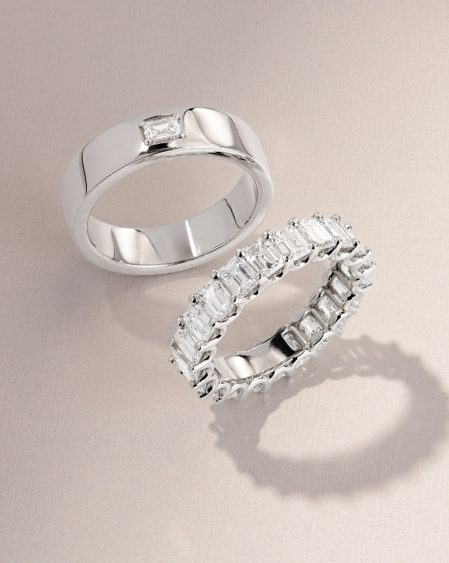 Two Canadian-made 18K white gold wedding rings with diamonds, including a classic polished band, on a ivory background.