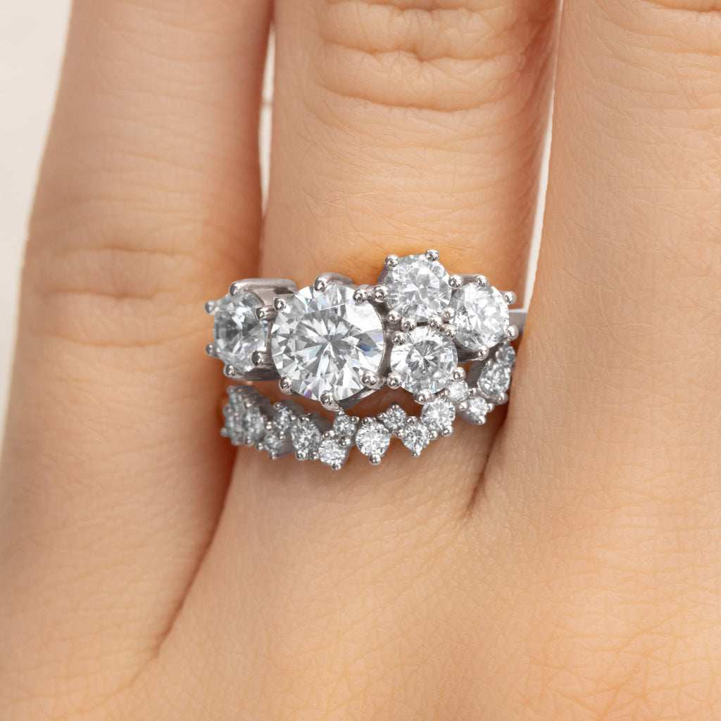 Close-up of a stacked diamond bridal set in 18K white gold. Canadian-made cluster engagement ring and curved wedding band.