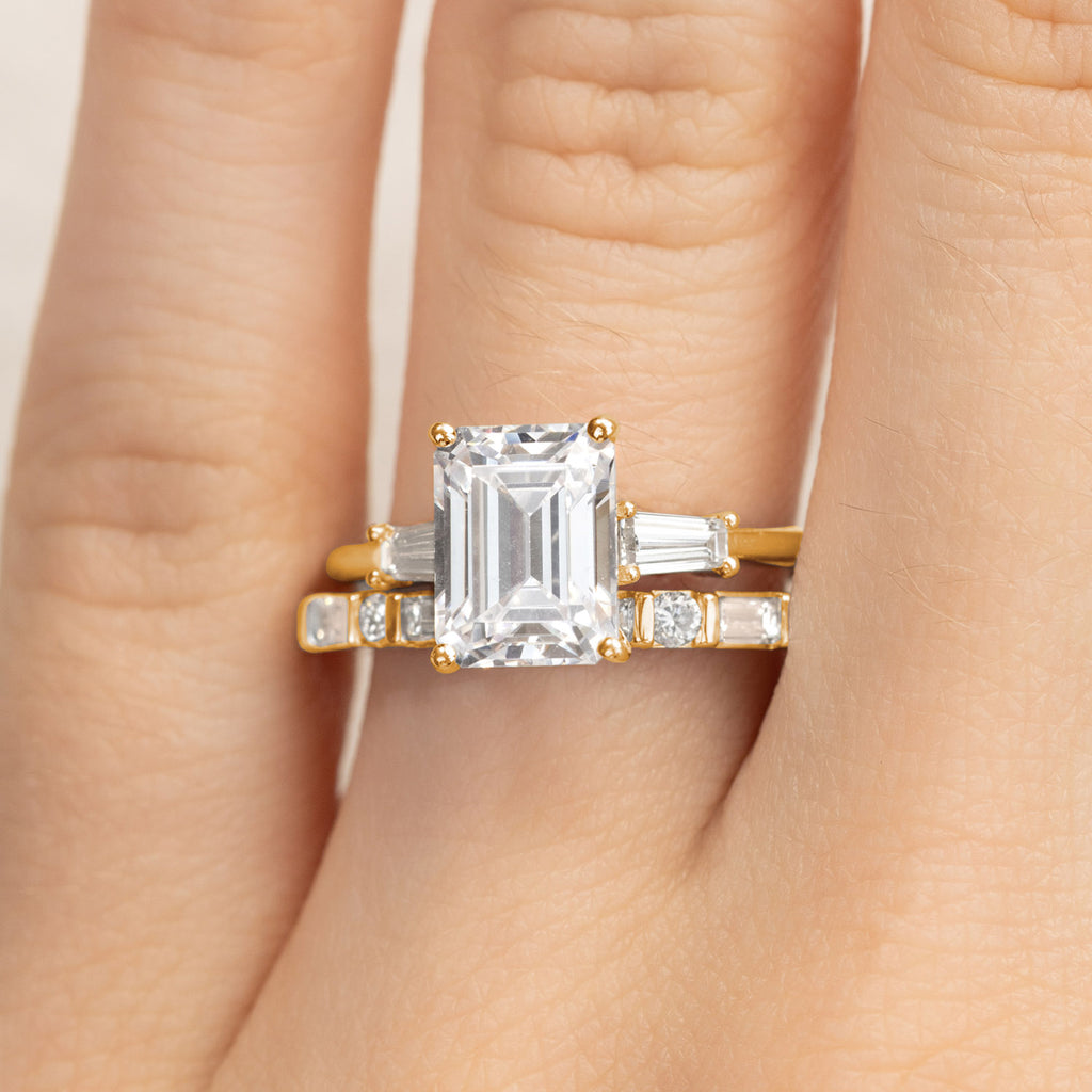 A Canadian-made bridal set with an emerald-cut diamond engagement ring and diamond wedding band in 18K yellow gold.