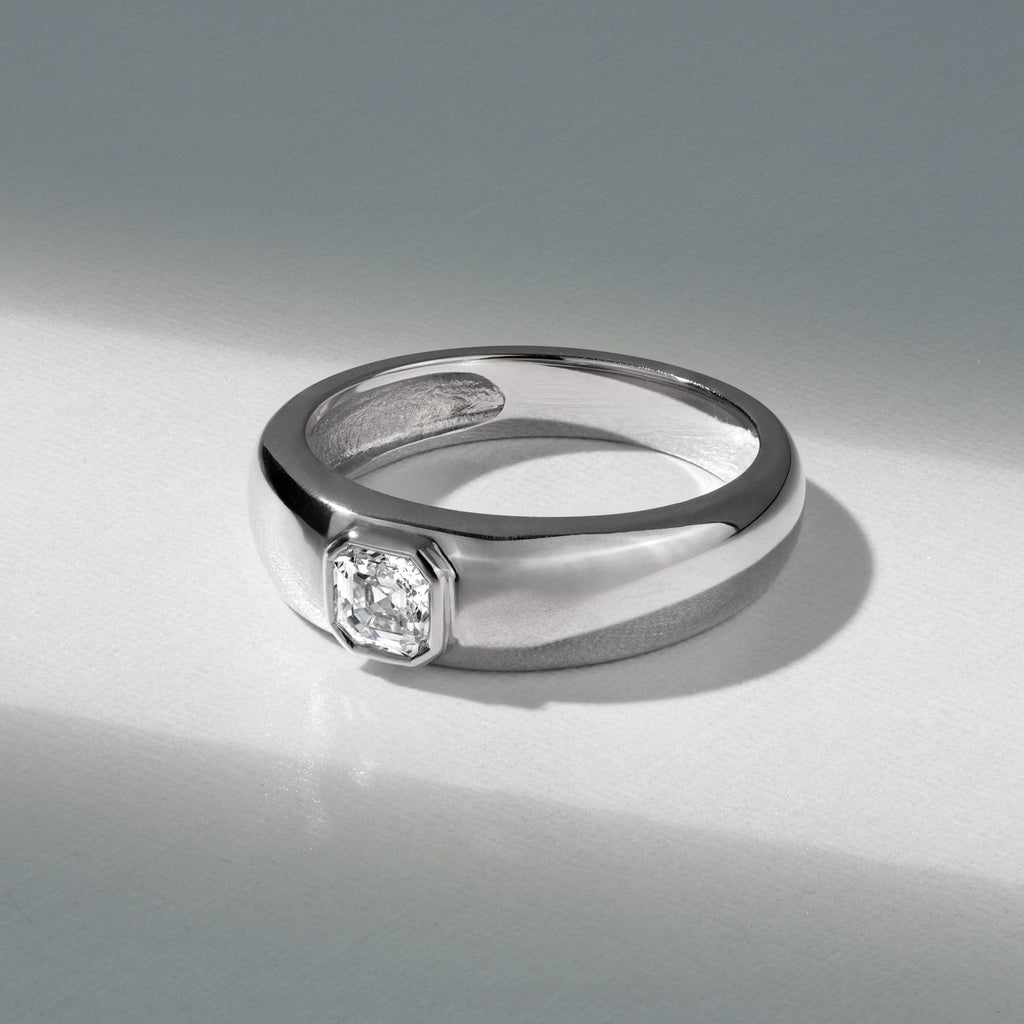A men's Canadian-made engagement ring with a wide 18K white gold band and a bezel-set Asscher-cut diamond.
